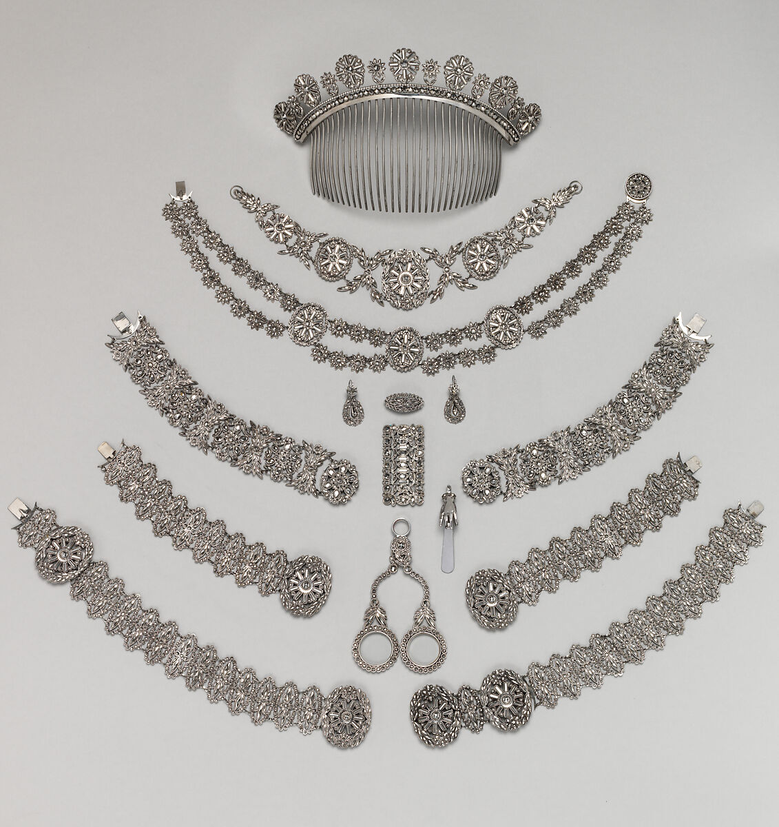 Real museum photograph of a French cut-steel parure arranged in its fitted leather case
